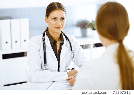 Woman-doctor and patient sitting and talking at hospital office. Green color blouse suits to therapist Woman-doctor and patient sitting and talking at hospital office. Green color blouse suits to therapist 71297812