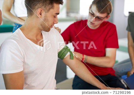 man wearing tourniquet on arm of injured person 71298196
