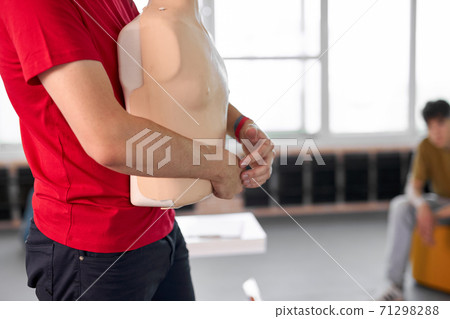 side view on male holding mannequin in hand durin first aid lesson 71298288