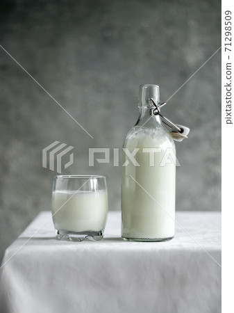 Kefir in a bottle and in a glass on a white table Kefir in a bottle and in a glass on a white table 71298509