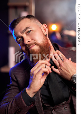 barber in a barber shop shaves his beard himself with scissors 71298875