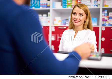 caucasian pharmacist is working with customer in modern drugstore 71299013