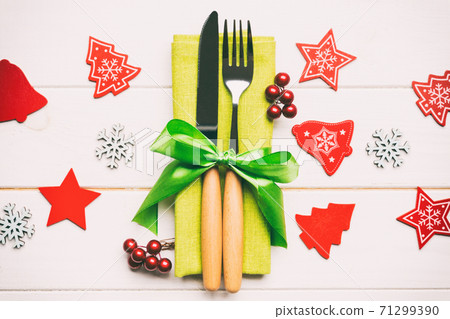 Top view of New Year dinner on wooden background. Festive cutlery on napkin with christmas decorations and toys. Close up of family holiday concept Top view of New Year dinner on wooden background. Festive cutlery on napkin with christmas decorations and toys. Close up of family holiday concept 71299390