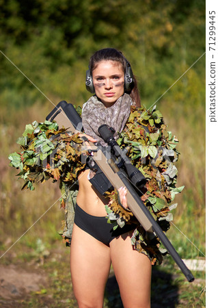 confident sexy woman in military style wear posing with rifle in ahnds, in the forest 71299445