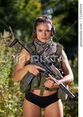 confident sexy woman in military style wear posing with rifle in ahnds, in the forest 71299564