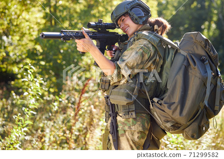 sportive woman soldier shooting with rifle machine gun in the forest 71299582