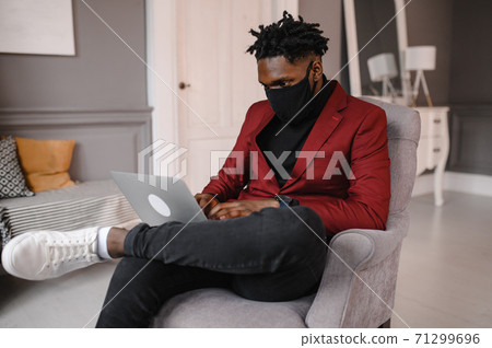 a black man works at a laptop close-up of his face. video conferences man wearing medical mask a black man works at a laptop close-up of his face. video conferences man wearing medical mask 71299696