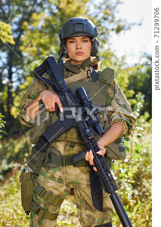 portrait of confident military woman with a gun in forest 71299706
