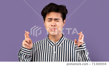 Hopeful young asian guy crossing his fingers 71300934