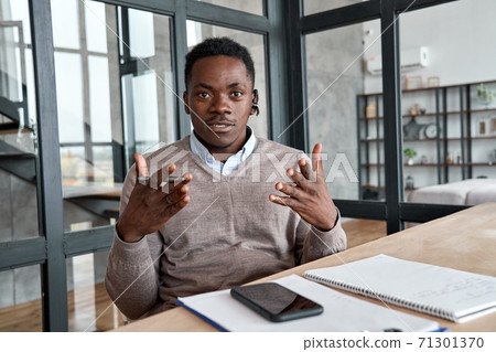 African business man wearing headset talking to camera, web cam view. 71301370