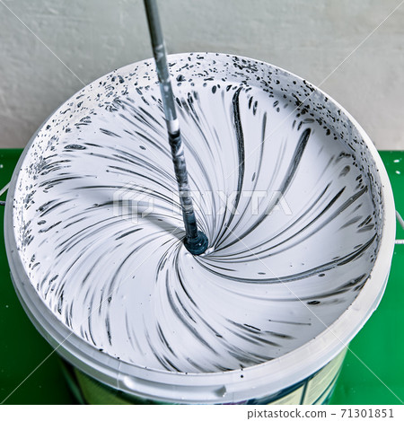 Painter combines paints for making color for painting walls with paddle whisk. Painter combines paints for making color for painting walls with paddle whisk. 71301851