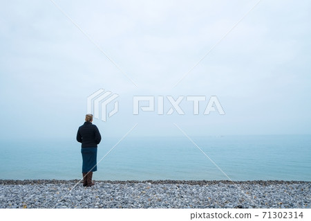 Woman looking out over a foggy sea Woman looking out over a foggy sea 71302314