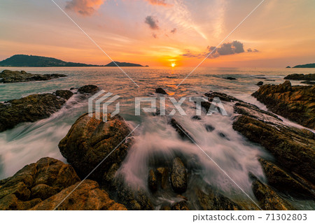 Long exposure image of Dramatic sky seascape with rocks in the foreground sunset or sunrise over sea scenery background. Long exposure image of Dramatic sky seascape with rocks in the foreground sunset or sunrise over sea scenery background. 71302803
