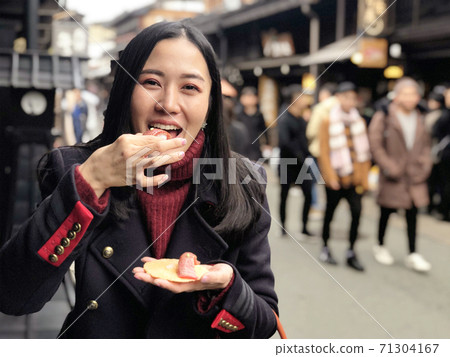 Young woman tourist enjoy eating Japanese street food Hida Beef Sushi and cracker at Takayama, Japan 71304167