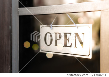 A business sign that says open on cafe or restaurant hang on door at entrance. A business sign that says open on cafe or restaurant hang on door at entrance. 71308231