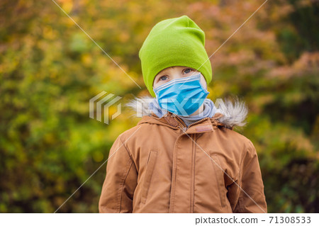 Portrait of little smiling child wearing a medical mask during COVID-19 coronavirus background of sunny autumn park 71308533