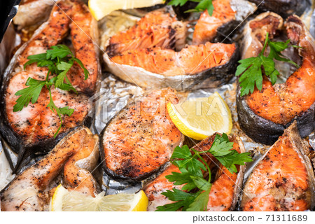 Soft focus. Baked chum salmon steaks with skin in the oven on foil. Soft focus. Baked chum salmon steaks with skin in the oven on foil. 71311689