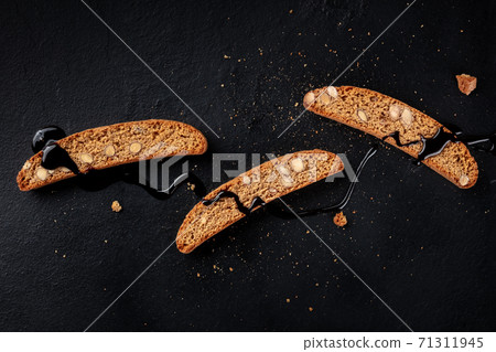 Biscotti. Italian almond cookies, overhead shot on a dark background Biscotti. Italian almond cookies, overhead shot on a dark background 71311945
