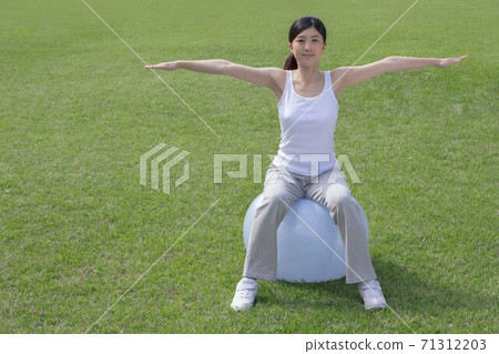 A woman training with a balance ball A woman training with a balance ball 71312203