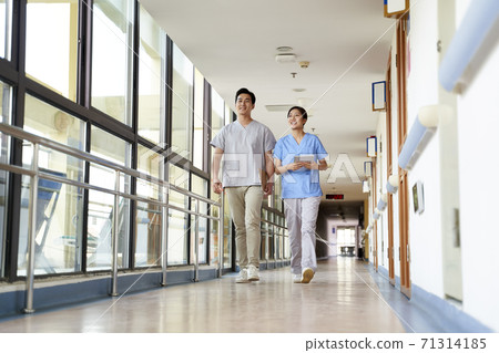 happy young asian physical therapists walking talking in hallway of nursing home 71314185
