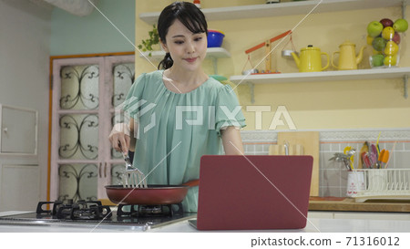 A young woman cooking while looking at the recipe site 71316012