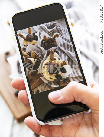 Girl makes a photo of cupcakes on a smartphone Girl makes a photo of cupcakes on a smartphone 71316814