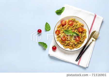 Fusilli - classic italian pasta from durum wheat with chicken meat, tomatoes cherry, basil in tomato sauce in white bowl, napkin, fork on blue wooden table Mediterranean cuisine Top view Flat lay 71316901