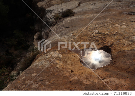 雨後的陽光美麗反射在一塊大石頭上的水坑里 71319953