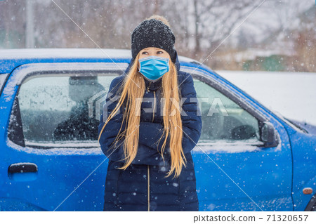 The woman wearing a medical mask during COVID-19 coronavirus was very froze in winter under snowfall. Winter problems The woman wearing a medical mask during COVID-19 coronavirus was very froze in winter under snowfall. Winter problems 71320657