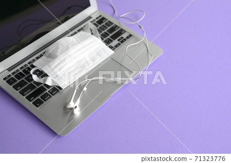 Ear phones on top of computer laptop and face mask 71323776