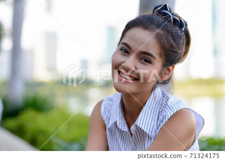 Happy young beautiful Asian woman at the park outdoors Happy young beautiful Asian woman at the park outdoors 71324175
