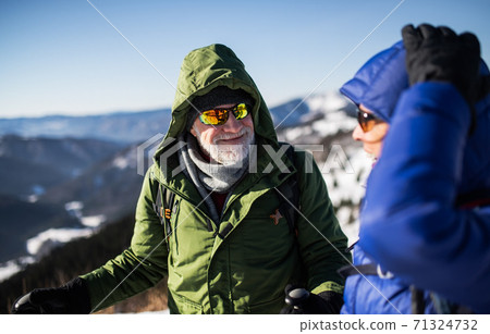 Senior couple hikers talking in snow-covered winter nature. Senior couple hikers talking in snow-covered winter nature. 71324732