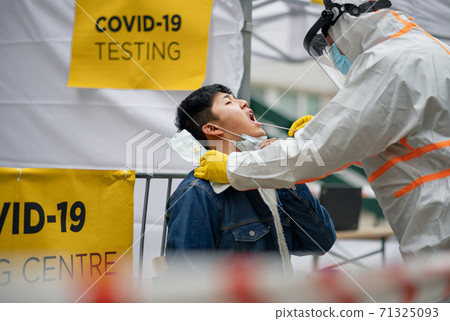 Young man in covid-19 testing center outdoors on street, coronavirus and taking swab concept. Young man in covid-19 testing center outdoors on street, coronavirus and taking swab concept. 71325093
