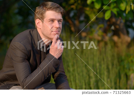 Young handsome businessman in suit thinking in nature outdoors Young handsome businessman in suit thinking in nature outdoors 71325663