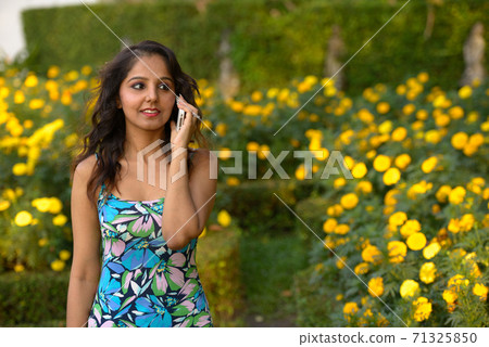 Happy young beautiful Indian woman talking on the phone at the park 71325850