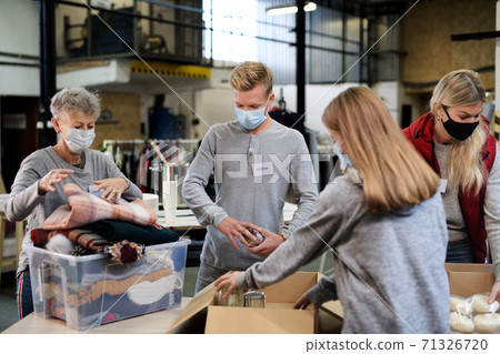 Group of volunteers in community charity donation center, food bank and coronavirus concept. 71326720