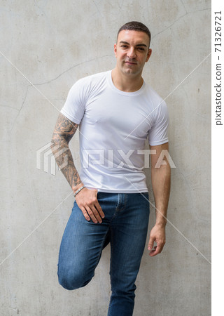 Portrait of handsome man with tattoos leaning against wall Portrait of handsome man with tattoos leaning against wall 71326721