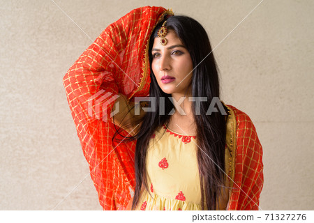 Portrait of beautiful young woman wearing traditional Indian dress 71327276