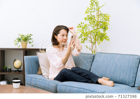 A woman looking at a smartphone with reading glasses A woman looking at a smartphone with reading glasses 71327398