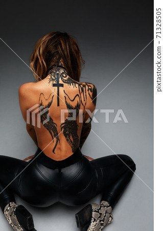 the back of a young girl with a tattoo . Tanned beautiful girl with a tattoo on the entire back 71328505