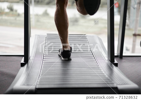 Unrecognizable Man running treadmill gym Athlete jogging indoor Weight loss workout jogger run gray wall background Cardio training 71328632