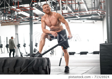 Man gym hammer hit tractor wheel hitting huge tire Athlete sportive man Middle adult handsome sportsman bodybuilder weightlifter ideal body Man gym hammer hit tractor wheel hitting huge tire Athlete sportive man Middle adult handsome sportsman bodybuilder weightlifter ideal body 71328924