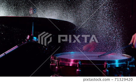 Freeze motion of drummer hitting drums with water splashes 71329420