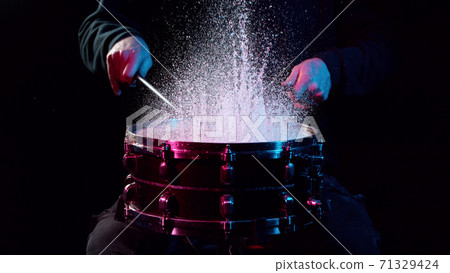 Freeze motion of drummer hitting drum with water splashes 71329424
