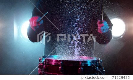 Freeze motion of drummer hitting drum with water splashes 71329425