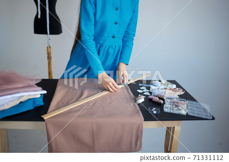 hands laying out sewing accessories on a piece of linen fabric hands laying out sewing accessories on a piece of linen fabric 71331112
