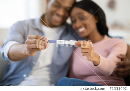 Young balck couple showing positive pregnancy test at home, selective focus on hands Young balck couple showing positive pregnancy test at home, selective focus on hands 71331492
