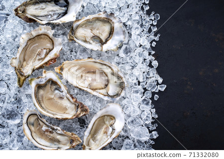 Fresh opened oyster with sliced lemon as top view on crushed ice with copy space right Fresh opened oyster with sliced lemon as top view on crushed ice with copy space right 71332080