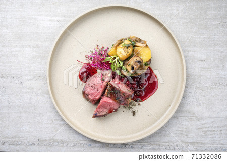 Modern style barbecue dry aged sliced venison fillet steak with potato mushroom terrine and cowberry sauce  71332086