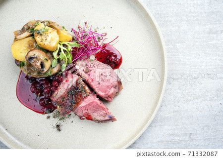 Modern style barbecue dry aged sliced venison fillet steak with potato mushroom terrine and cowberry sauce  71332087